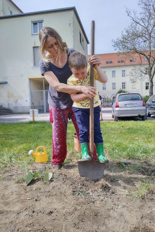 Frau und Kind schaufeln mit einem Spaten ein Loch