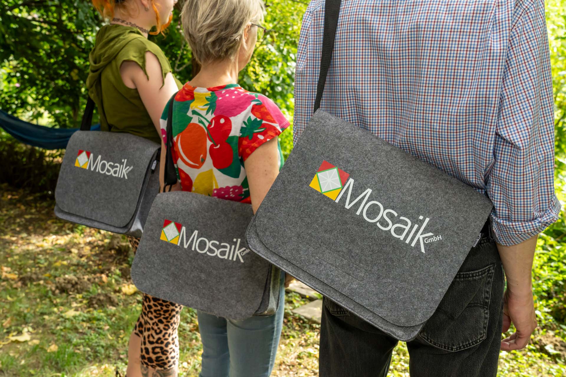 drei Personen mit einer Mosaik-Tasche